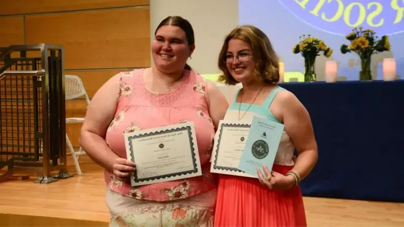 Two female students at the Delta Alpha Pi induction ceremony. 